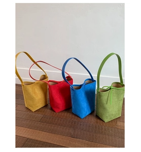 Detail view of colorful suede tote bags in yellow, red, blue and green with slim handles