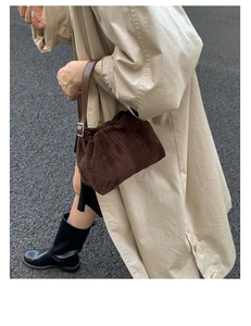 Detail of dark brown suede cloud bag showing soft pleated texture and leather strap buckle