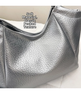 Détail du sac cabas argenté présentant un tissu souple et un motif grainé classique