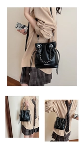 Detail of black drawstring bucket bag featuring silver chain and leather texture