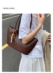 Detail of dark brown woven tote bag with retro bead tassel on a street scene model