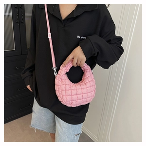 Detail of pink quilted puff dumpling bag with nylon texture and adjustable shoulder strap