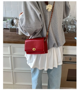 Rear view of a woman wearing a vintage red leather square bag with gold chain strap