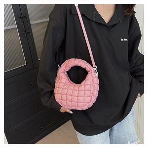 Close-up of pink quilted dumpling bag showing the puffy fabric and round top handle