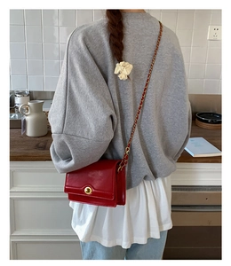 Close-up of red vintage crossbody bag with golden buckle and chain strap detail