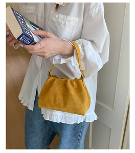 Detail of yellow suede dumpling bag showing ruched leather texture and silver buckle