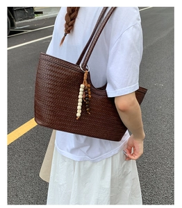Close-up of deep brown woven tote bag featuring beaded tassels and fine craftsmanship