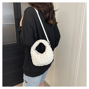 Detailed view of white quilted crossbody bag worn by model showing its soft puffer texture