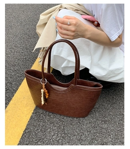 Detail of dark brown woven texture tote bag with wooden bead tassel and double handles