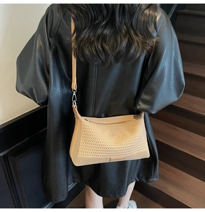 Dettaglio di una borsa a tracolla intrecciata beige con cinturino in pelle su una modella