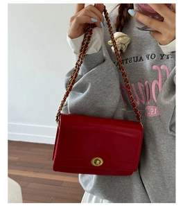 Detail of red rectangular chain bag with vintage gold swivel lock and leather strap
