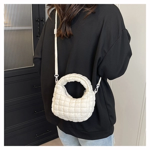 Detail of a white quilted puffer bag showing its fluffy texture and handle on a model