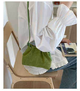 Dettaglio borsa a secchiello in camoscio verde con tracolla e texture plissettata