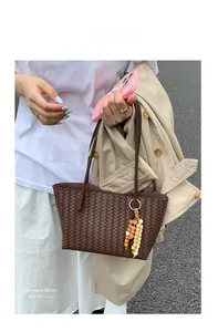 Detail of dark brown woven tote bag featuring a boho wooden bead tassel and slim straps