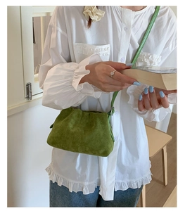 Close-up of grass green suede crossbody bag with elegant pleated design and leather strap