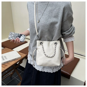 Detail of white leather drawstring bucket bag with silver chain and logo text