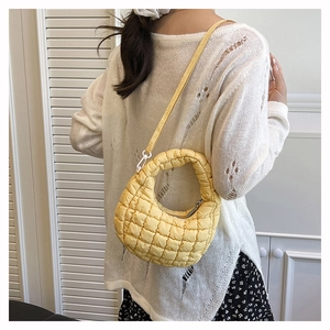 Detail of yellow quilted dumpling bag with textured bubble pattern and adjustable strap