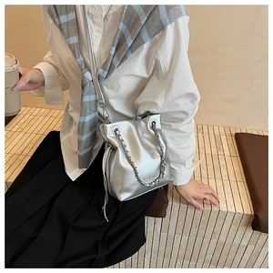 Close-up of metallic silver bucket bag with drawstring closure and silver chain handle