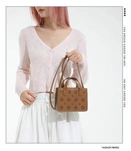 Gros plan d'un sac en cuir marron avec motifs floraux rivetage et bandoulière amovible