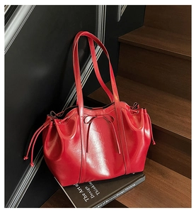 Detail of red drawstring tote bag with decorative bow and glossy faux leather texture