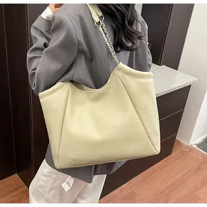 Détail du cabas en cuir beige grainé avec bandoulière en chaîne métallique argentée