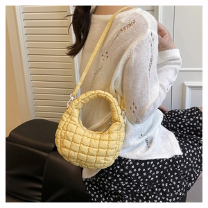 Close-up of bright yellow quilted bubble bag with fine metal hardware and zipper detail