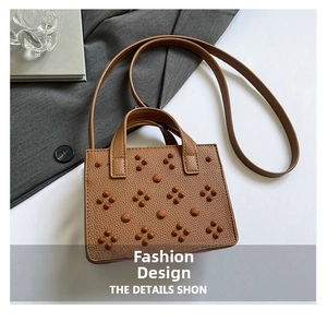 Détail du sac à main marron en cuir litchi avec rivets décoratifs et poignée supérieure