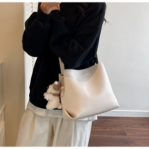 Detail of minimalist cream bucket bag with a cute plush puppy charm accessory