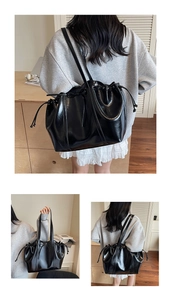 Detail of black glossy patent leather bucket bag with stylish drawstring bow decoration