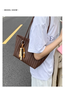 Detail of a large woven tote bag in dark brown with a beaded tassel on shoulder