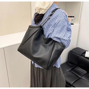 Détail d'un grand sac cabas en cuir noir à texture litchi et bandoulière chaîne