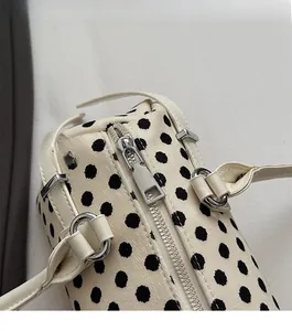 Detail van de zilveren rits en het polkadotpuntpatroon op de grote schoudertas dames