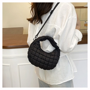 Chic black quilted puff bag shown with crossbody strap on a casual model outfit