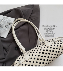 Detail van de hobo-tas met stippen en lederen riem op een grijze blazer