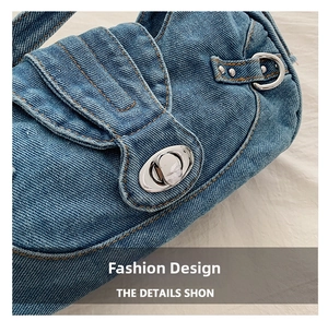 Detail of blue denim shoulder bag with silver turn-lock and orange stitching accents