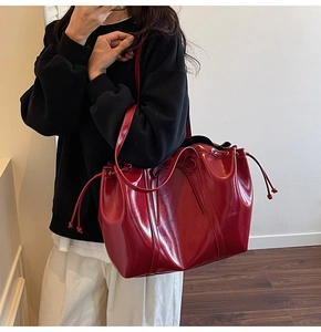 Close-up of dark red glossy tote bag featuring a drawstring closure and bow detail