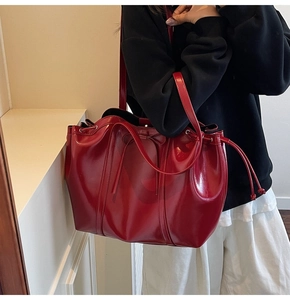 Close-up of bright red patent leather tote bag with drawstring and bow detail