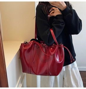 Red glossy patent leather tote bag with bow detail shown on a female model shoulder