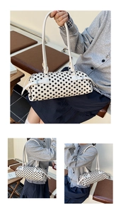 Detailopname van een witte cilindertas met polkadots en verstelbare metalen gespen