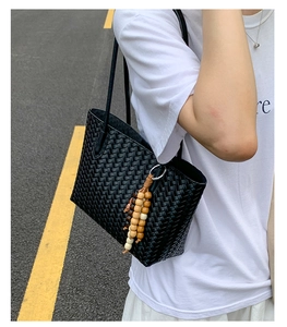 Detail of hand-woven black tote bag with vintage texture and wooden bead tassel accessory