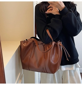 Detailed view of the glossy dark brown tote bag with stylish drawstring bow accent
