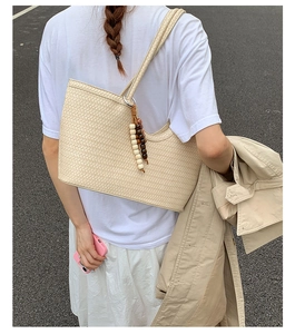 Detailed close-up of a beige woven tote bag featuring decorative wooden bead accents