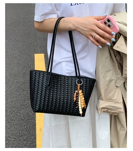 Close-up of black woven tote bag with ethnic style wooden bead tassel detail