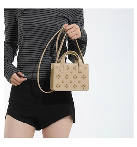 Détail d'un sac à rabat beige clouté avec texture structurée et rivets métalliques