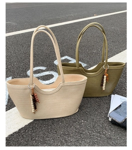 Detail of woven tote bags in beige and olive green with decorative bead tassel charms