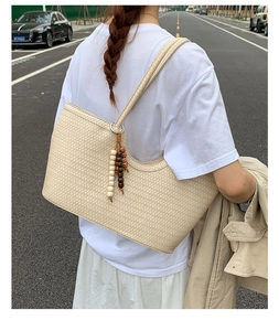Detail of beige woven tote bag showing straw texture and decorative wooden beads