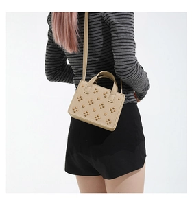 Détail du sac beige en cuir grainé avec motifs floraux de rivets et bandoulière fine