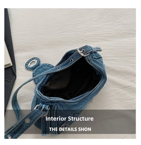 Detail view of the denim saddle bag interior with black lining and metal eyelet strap