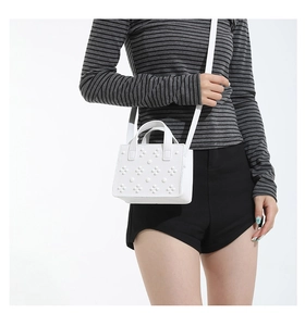 Détail du sac à main en cuir grainé blanc avec texture cloutée et poignée supérieure