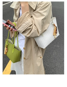 Detail of woven tote bags with ethnic wooden bead charms in green and white styles